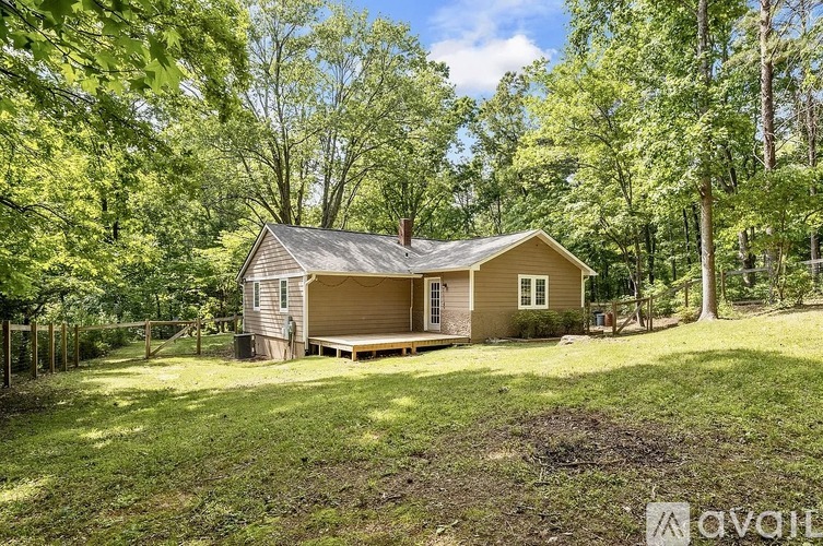 A house with a porch is surrounded by trees and grass.