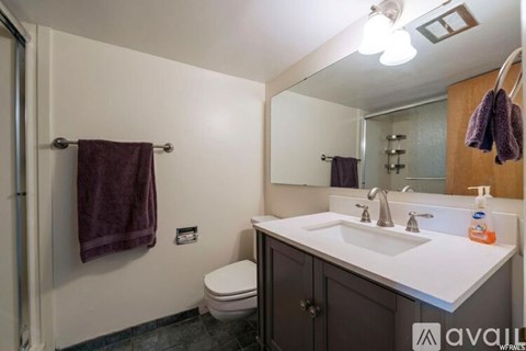 A bathroom with a toilet, sink, mirror, and towel rack.