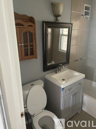 A bathroom with a toilet, sink, and mirror.