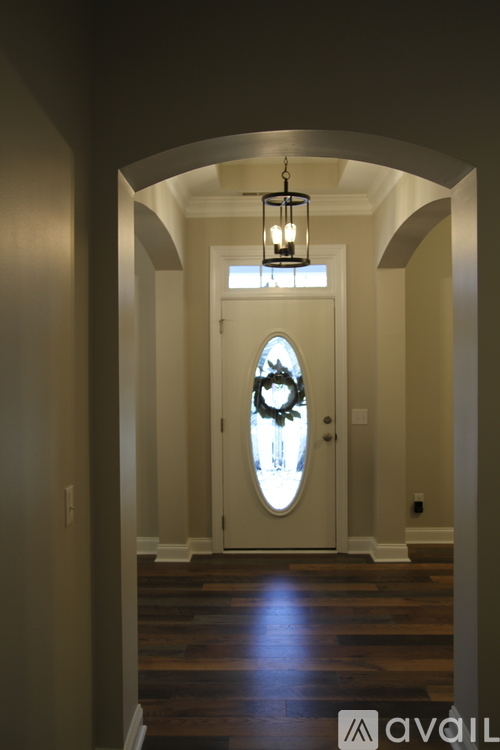 A hallway with a door and a light hanging from the ceiling.