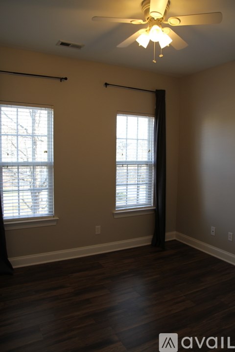 A room with a ceiling fan and two windows.