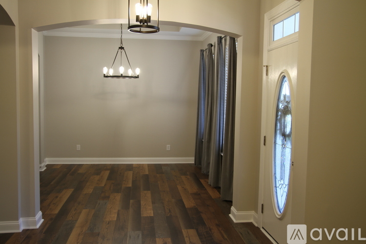 A room with wooden floors and a chandelier hanging from the ceiling.