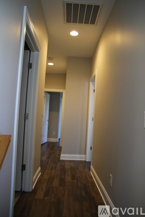 A hallway with wood floors and white walls.