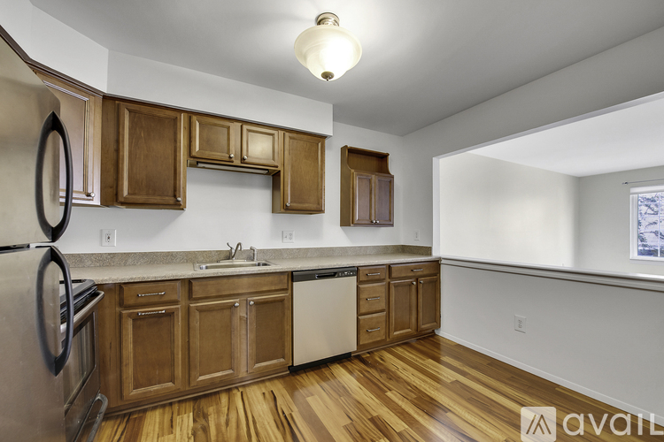 A kitchen with wooden cabinets and a stainless steel dishwasher.