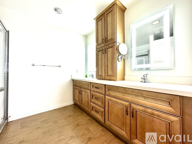 A wooden bathroom vanity with a mirror and a cabinet.