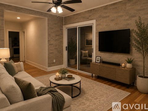 A living room with a couch, a coffee table, a ceiling fan, and a television mounted on the wall.