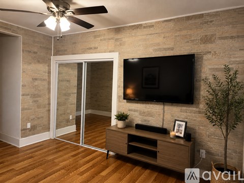 A room with a television mounted on a stone wall and a wooden floor.