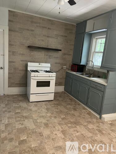 A kitchen with a white stove and a tiled floor.