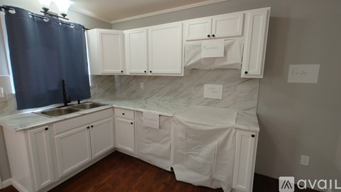 A kitchen with white cabinets and a sink is available for rent.