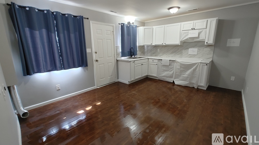 A room with wooden floors and white walls is available for rent.