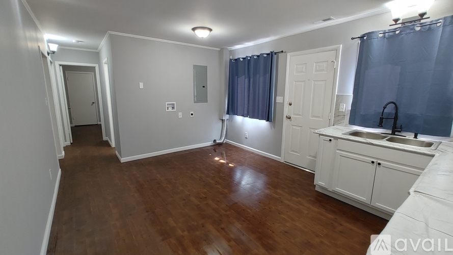 A kitchen with white cabinets and a wooden floor.