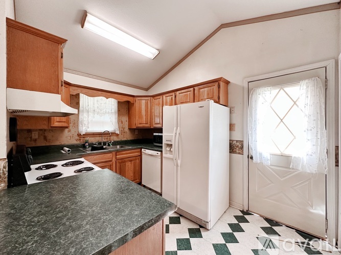 A kitchen with a black stove top oven and a white refrigerator.