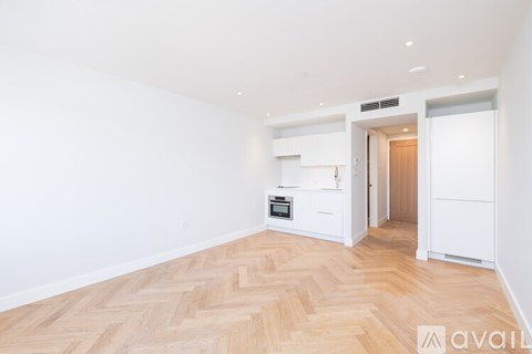 A spacious room with wooden flooring and white walls.