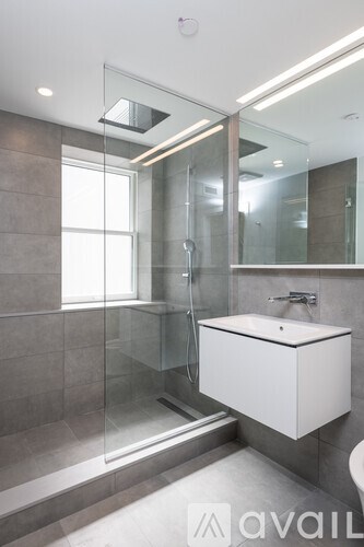 A modern bathroom with a walk-in shower and a white cabinet.