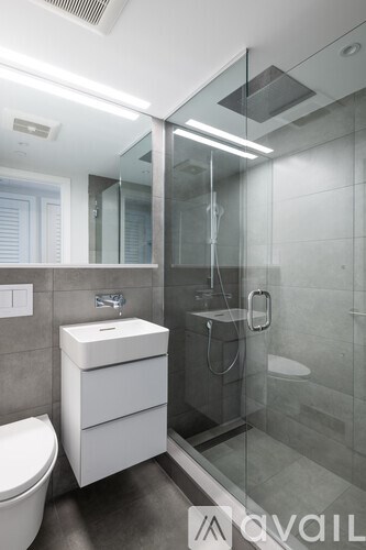 A modern bathroom with a glass shower stall and a white sink.