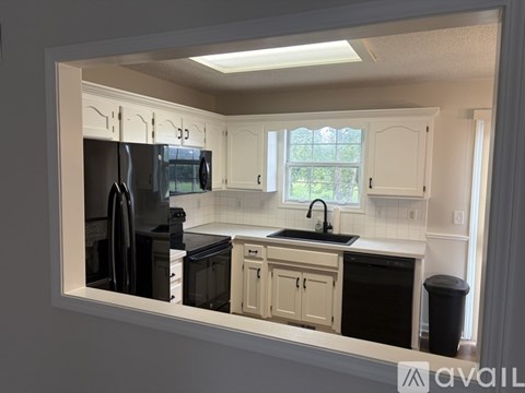 A kitchen with white cabinets and a black fridge.