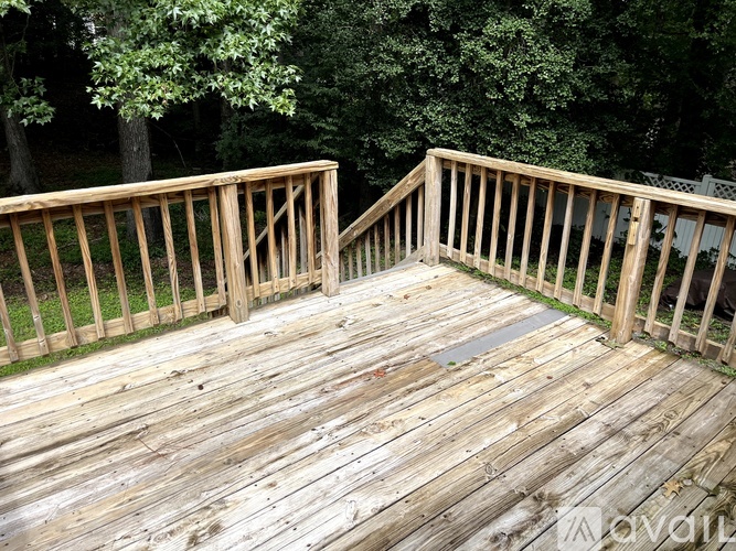 A wooden deck with a railing and a tree in the background.