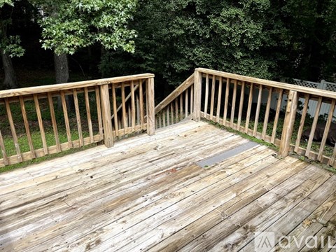 A wooden deck with a railing and a tree in the background.