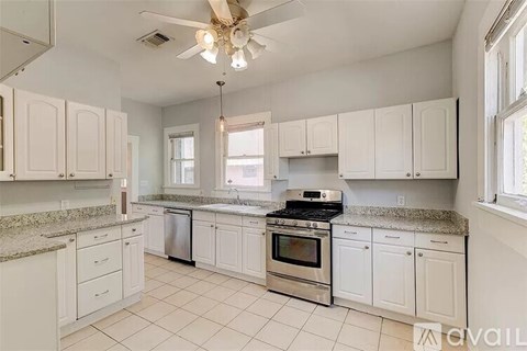 A kitchen with white cabinets and a fan.
