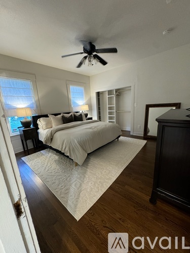 A bedroom with a large bed and a ceiling fan.