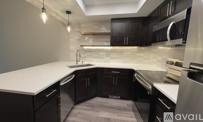 A modern kitchen with dark wood cabinets and a white countertop.