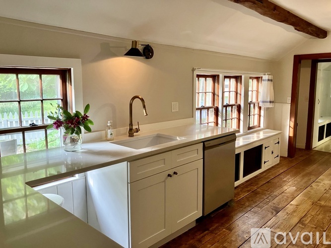A kitchen with a sink, a window, and wooden floors.