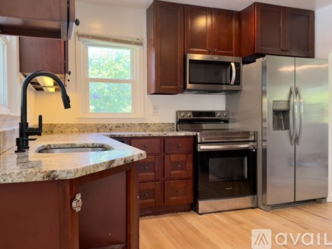 A kitchen with brown cabinets and a marble countertop.
