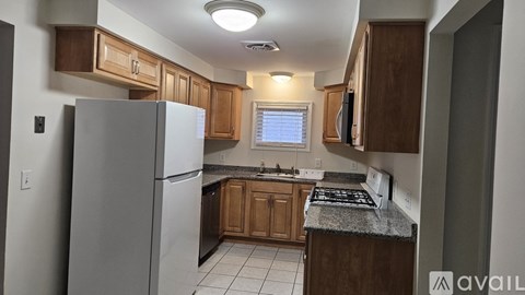 A kitchen with a refrigerator, cabinets, and a stove top oven.