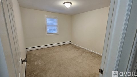 A room with a carpeted floor and a window with blinds.