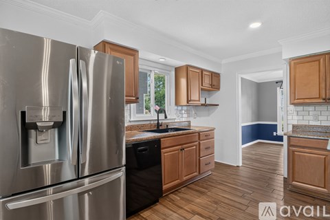 A modern kitchen with a stainless steel refrigerator and wooden cabinets.
