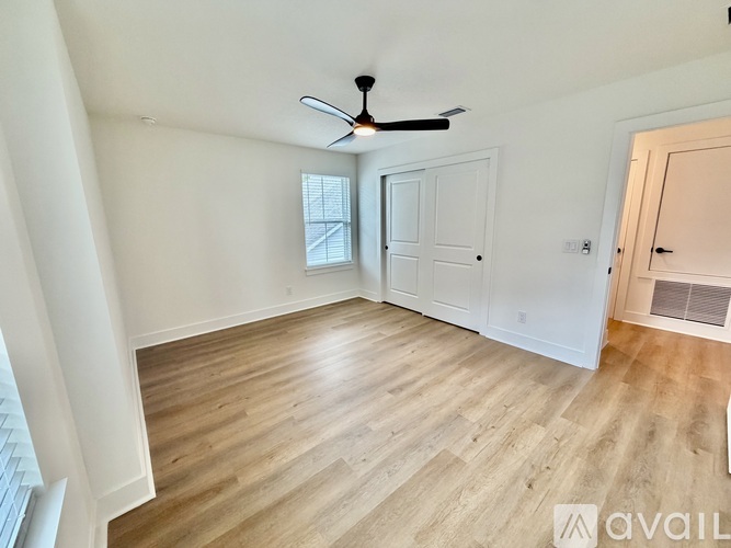 A room with a ceiling fan and wooden flooring.