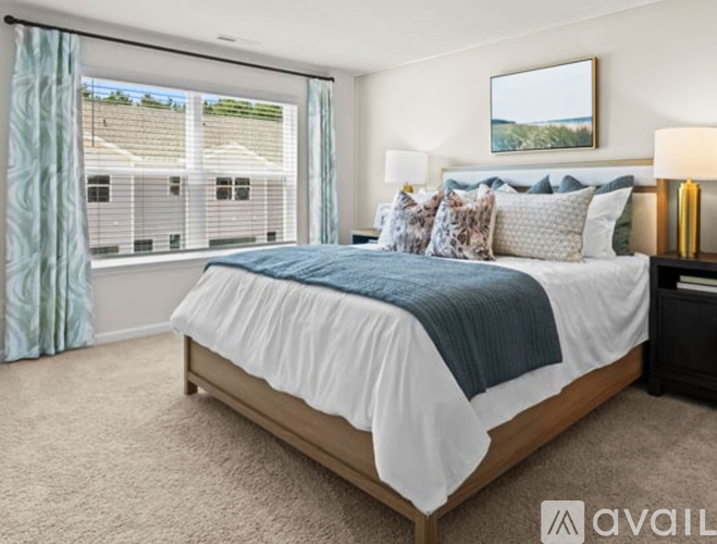 A bedroom with a large bed and a window overlooking a residential area.