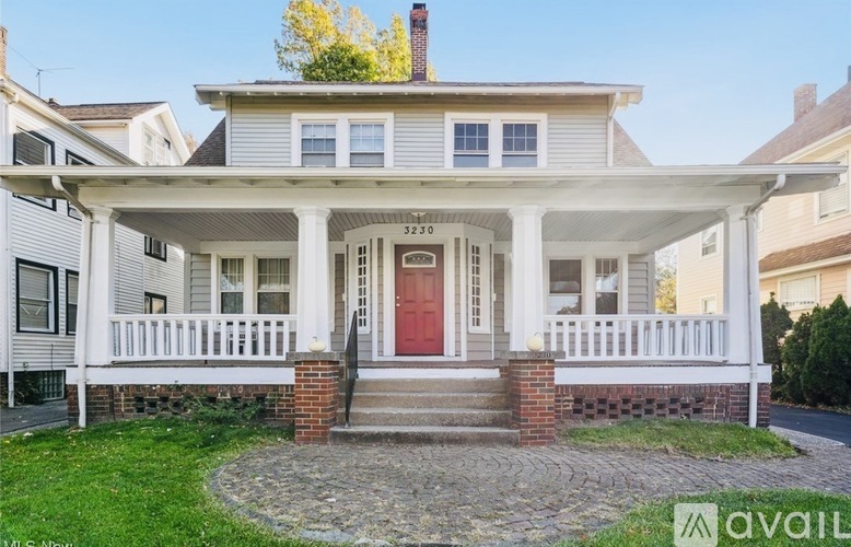 A white house with a red door and a brick base.
