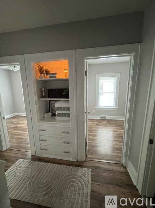 A room with a rug on the floor and a cabinet with a mirror above it.