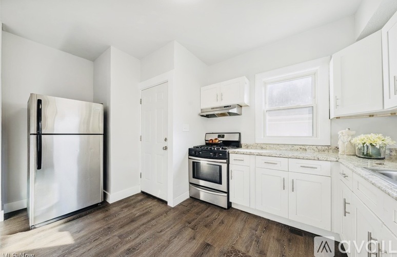 A white kitchen with a refrigerator, oven, and cabinets.