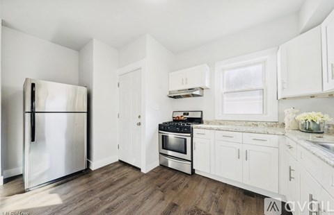 A white kitchen with a refrigerator, oven, and cabinets.