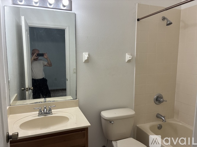 A man is taking a picture of a bathroom with a mirror.