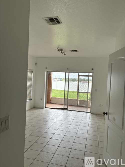 A room with a tiled floor and a sliding glass door leading to a balcony.