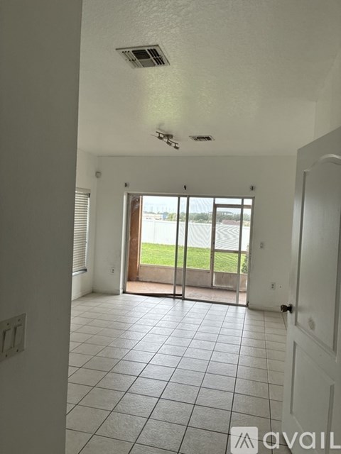 A room with a tiled floor and a sliding glass door leading to a balcony.