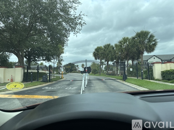 A car is driving down a street with a gated entrance on the right.