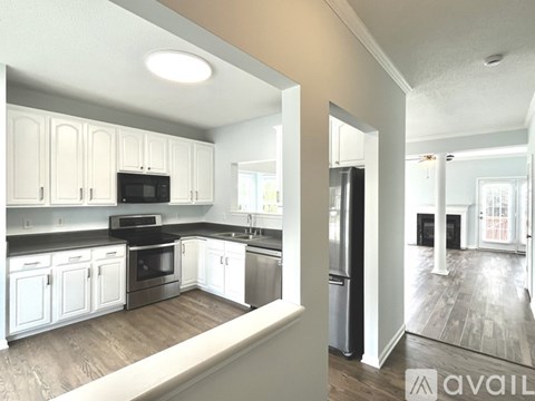 A kitchen with white cabinets and a black countertop.