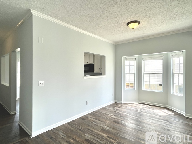 A spacious room with wood flooring and white walls.