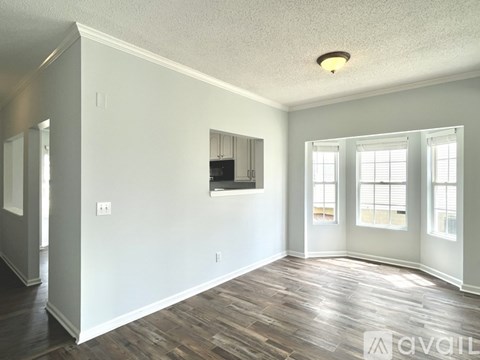 A spacious room with wood flooring and white walls.