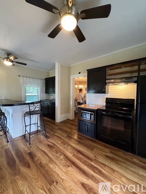 A kitchen with a black oven and a ceiling fan.