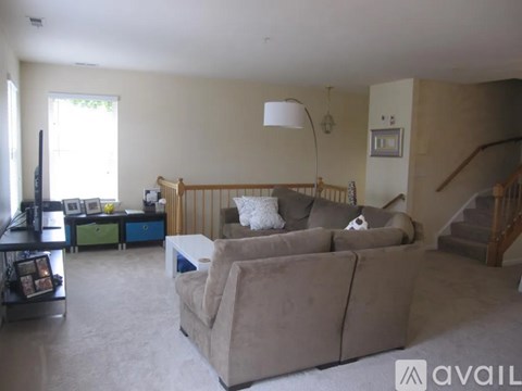 A living room with a large couch and a staircase.