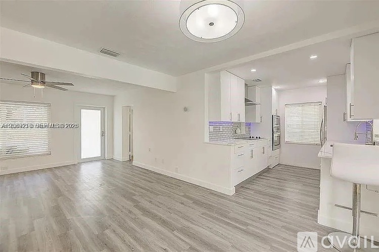 A spacious room with a fan and a kitchen area.