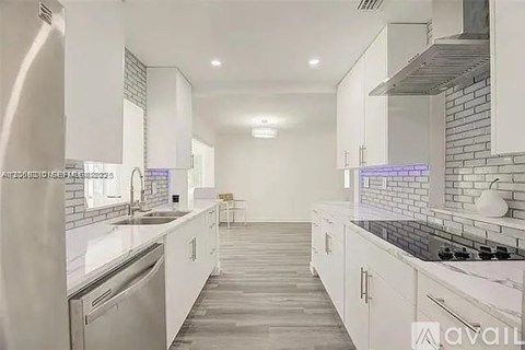 A modern kitchen with white cabinets and a marble countertop.