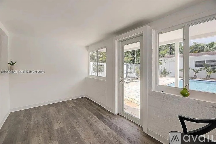 A room with a wooden floor and sliding glass doors leading to a pool area.