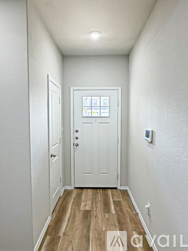 A hallway with a white door and wooden floor.