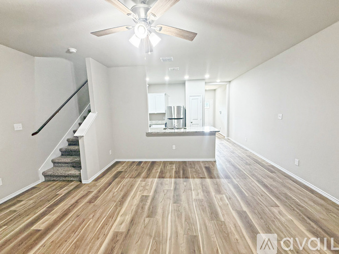 A spacious room with wooden flooring and a staircase leading to the upper level.